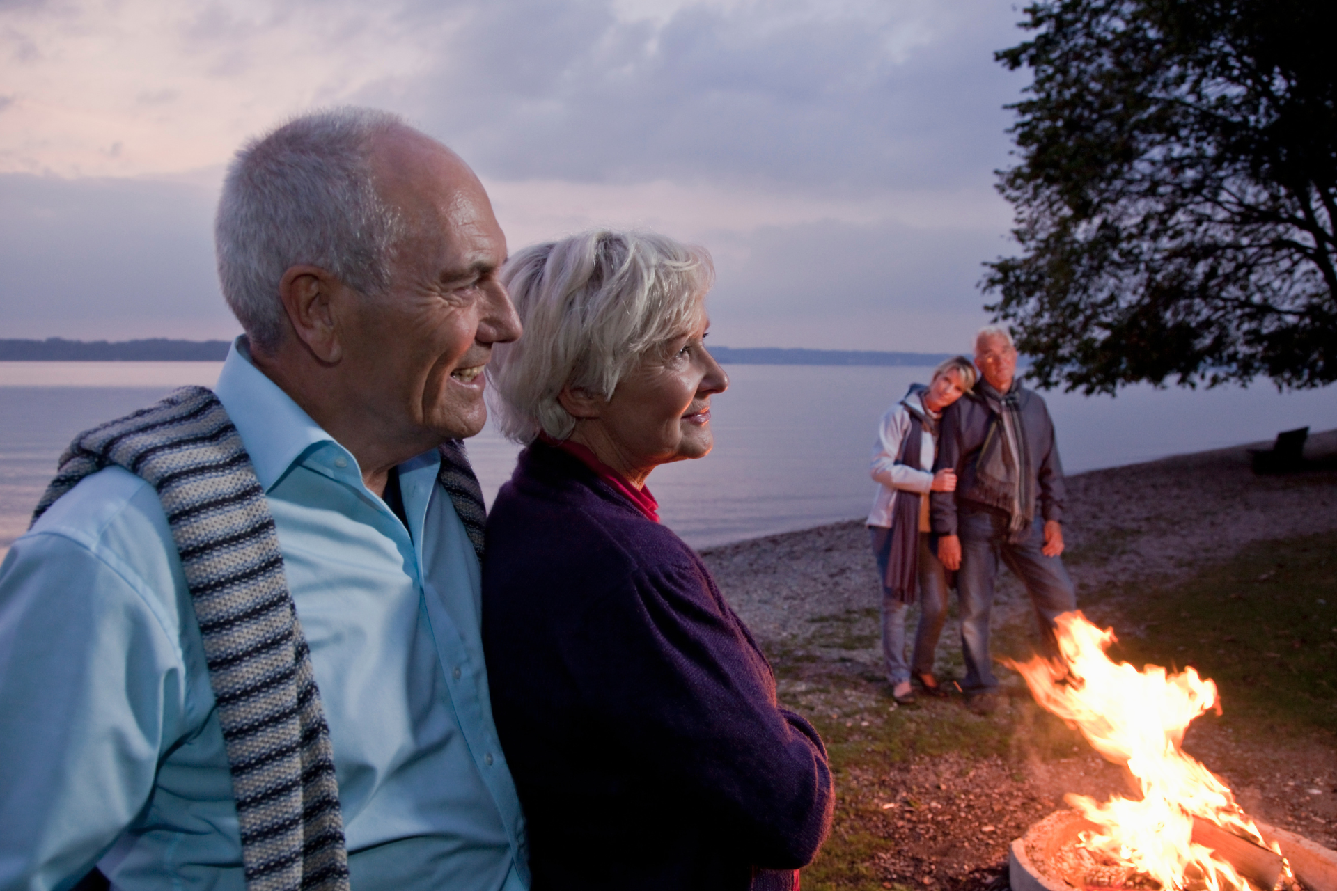 Two senior couples standing around a campfire