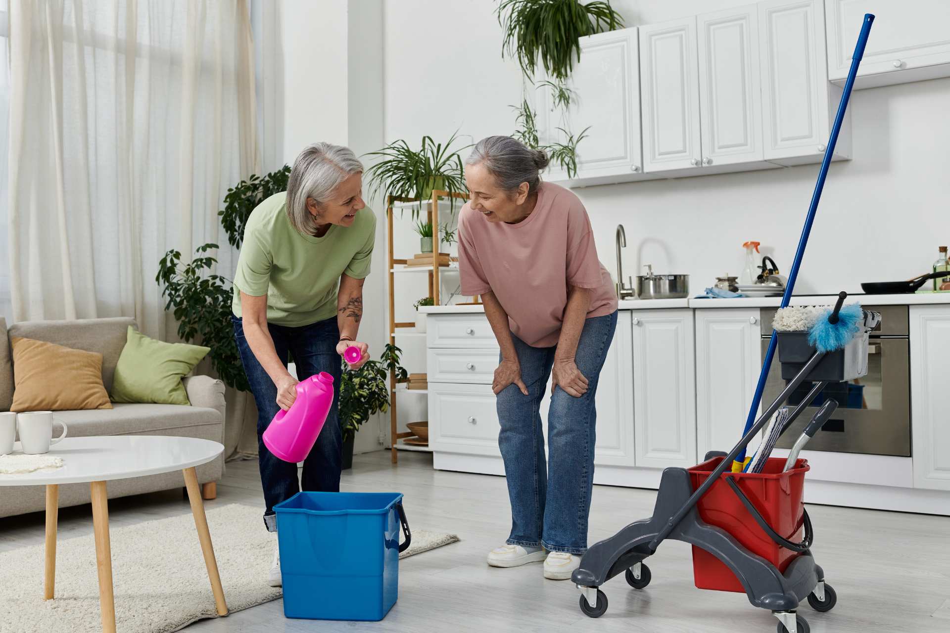Two senior women cleaning their home together.